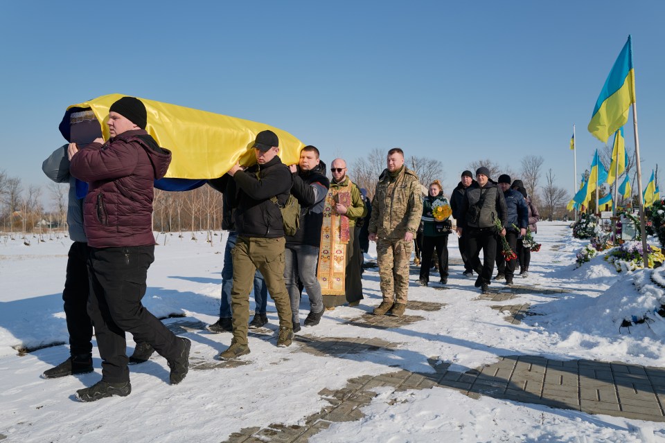 Funeral procession carrying a coffin draped in a Ukrainian flag.