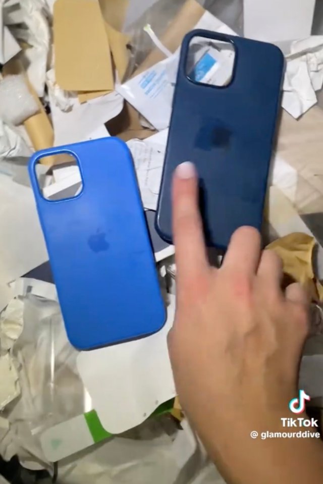 A hand holding two blue iPhone cases found while dumpster diving.