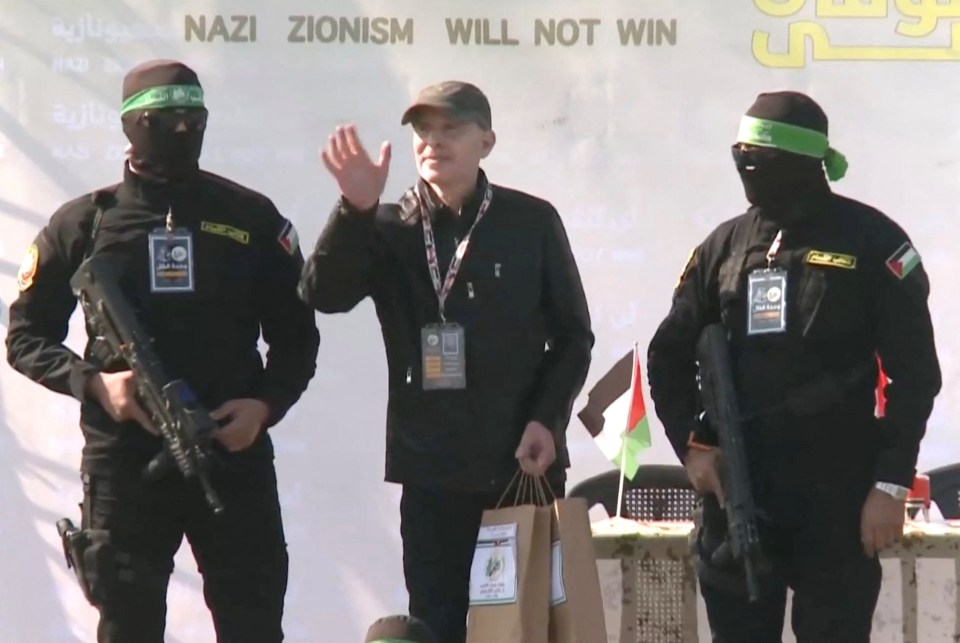 Released hostage waving goodbye, flanked by Hamas militants.