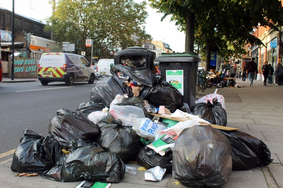 Overflowing garbage bags on a city street.