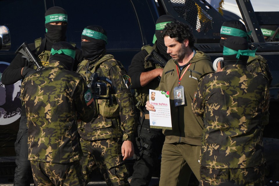 An Israeli hostage walks next to Hamas fighters in Gaza.