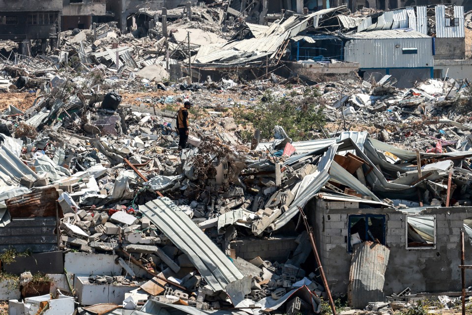 A man stands amidst the rubble of destroyed buildings in Khan Yunis, Gaza.