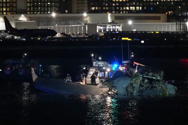 Plane wreckage in the water at night, with emergency responders present.