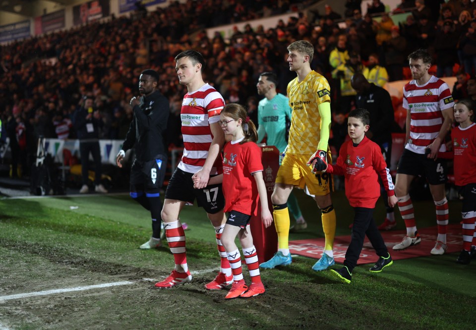 Doncaster Rovers' Owen Bailey and mascots walk onto the pitch.