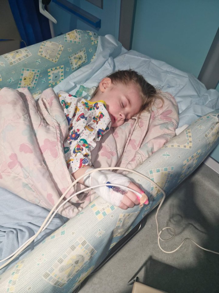 A young girl sleeping in a hospital bed with an IV line.