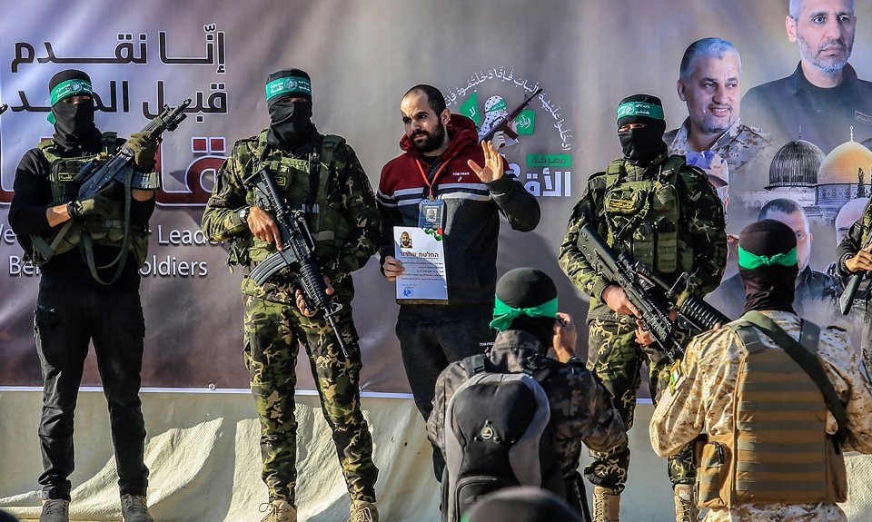 Hamas fighters hand over an Israeli hostage.