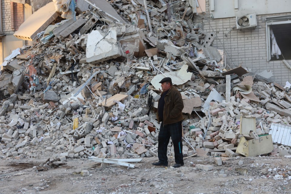 A man stands near a pile of rubble from a destroyed building in Kherson, Ukraine.