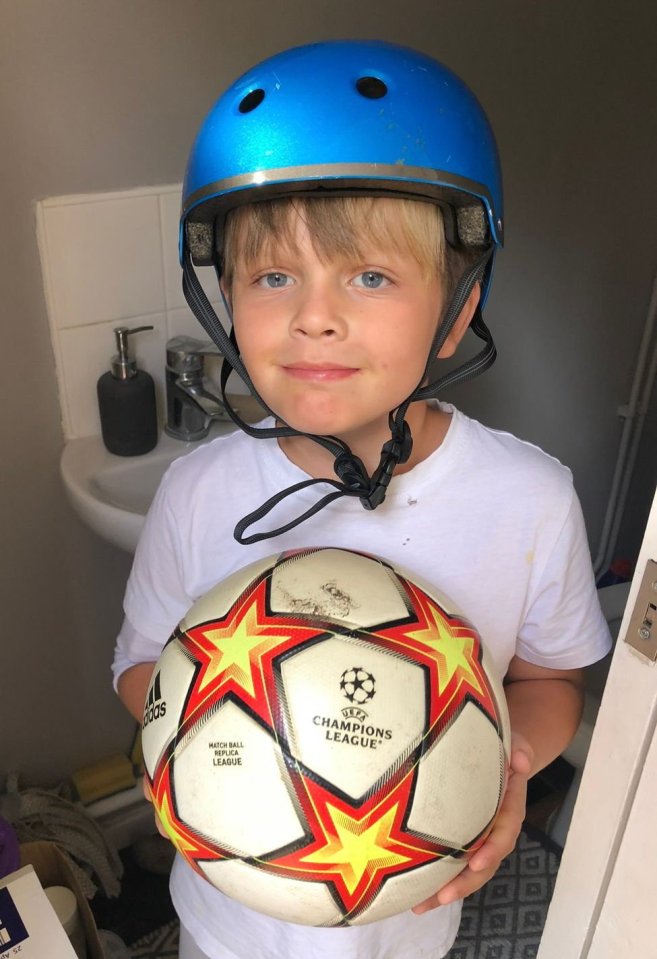 Boy wearing a blue helmet holding a soccer ball.