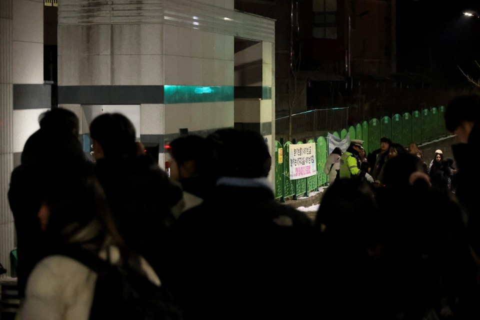 People gathered outside a South Korean elementary school at night following a student's death.