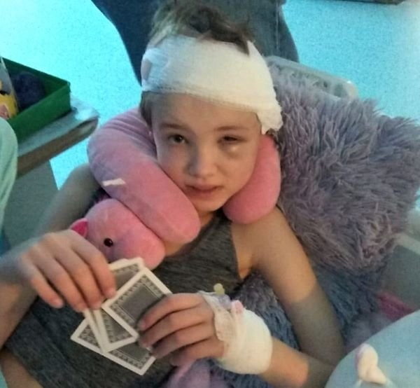 Teenage girl recovering from a quad bike accident, holding playing cards.