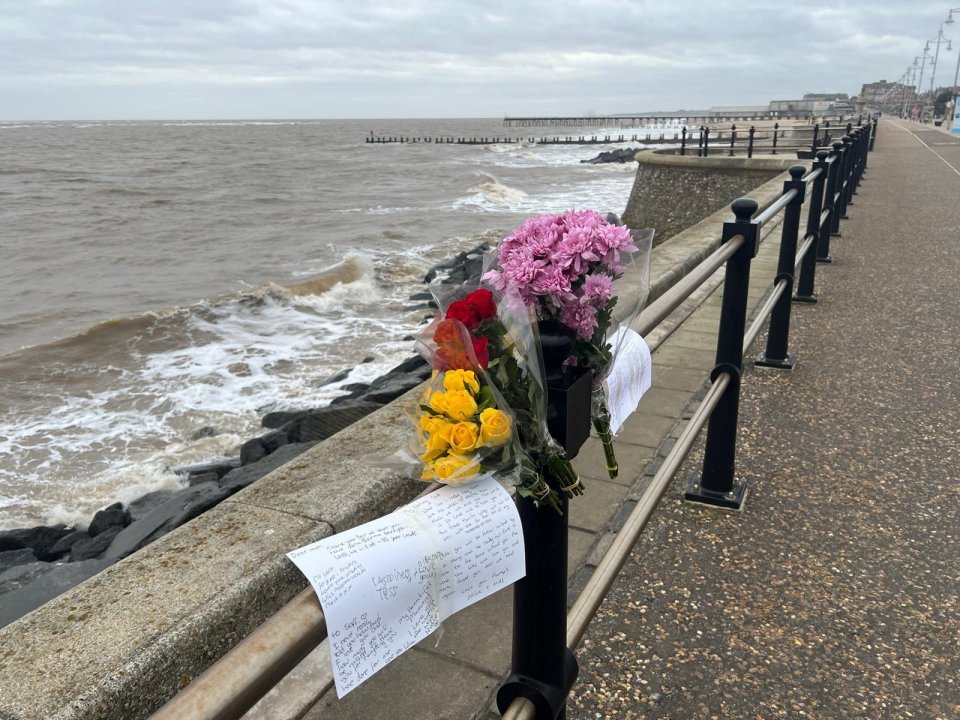 Floral tributes on a seafront railing.