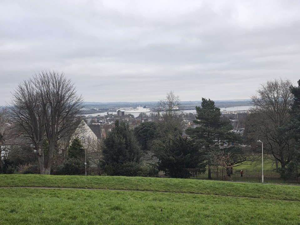 Overlook of a town and river with a ferry in the distance.