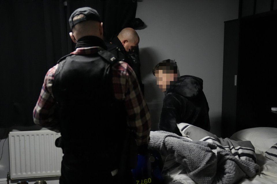 Police officers arresting a suspect in a bedroom.