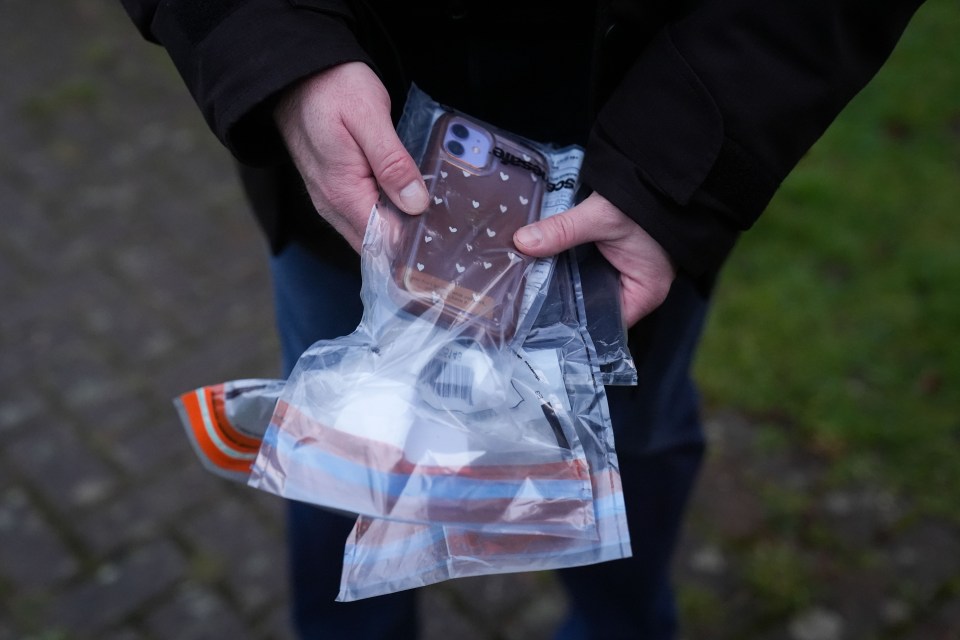 A person holds evidence bags containing cell phones seized during a police raid.