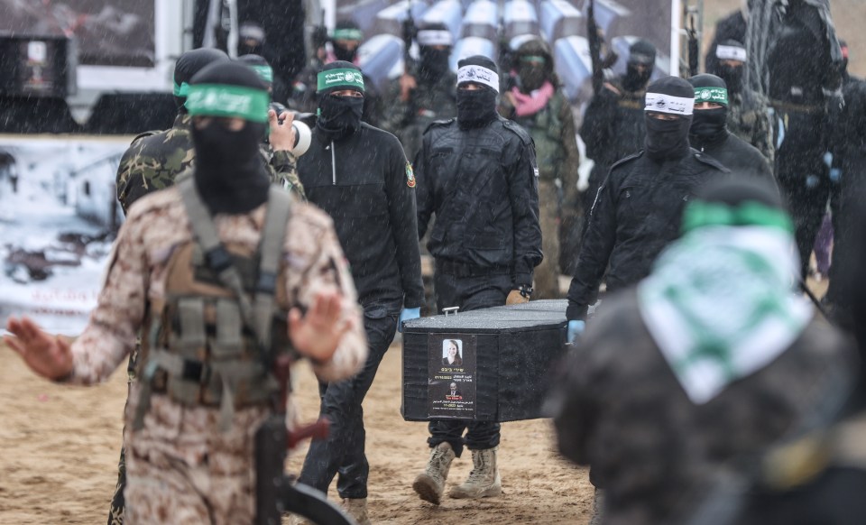 Al-Qassam Brigades members carrying a casket in the rain.