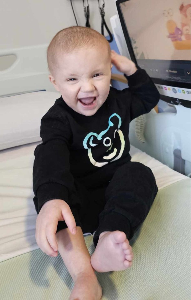 Smiling toddler in a hospital bed.