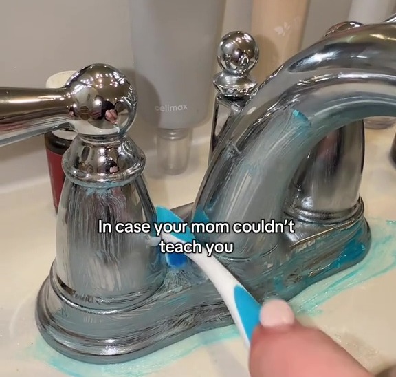 Cleaning a bathroom sink faucet with a toothbrush.