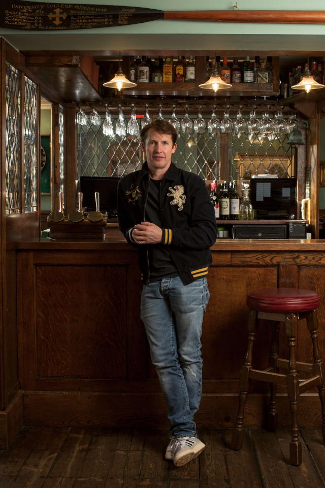 James Blunt standing behind the bar of his pub, The Fox & Pheasant.