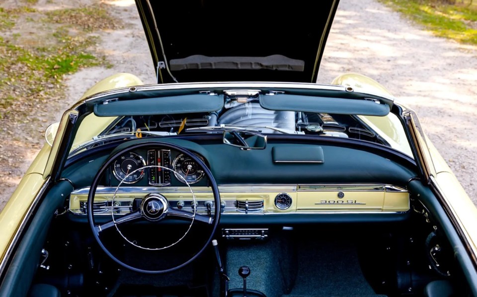 Interior view of a yellow Mercedes-Benz 300 SL Roadster with the hood open.