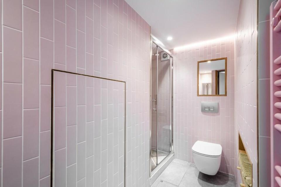 Pink bathroom with shower, toilet, and mirror.