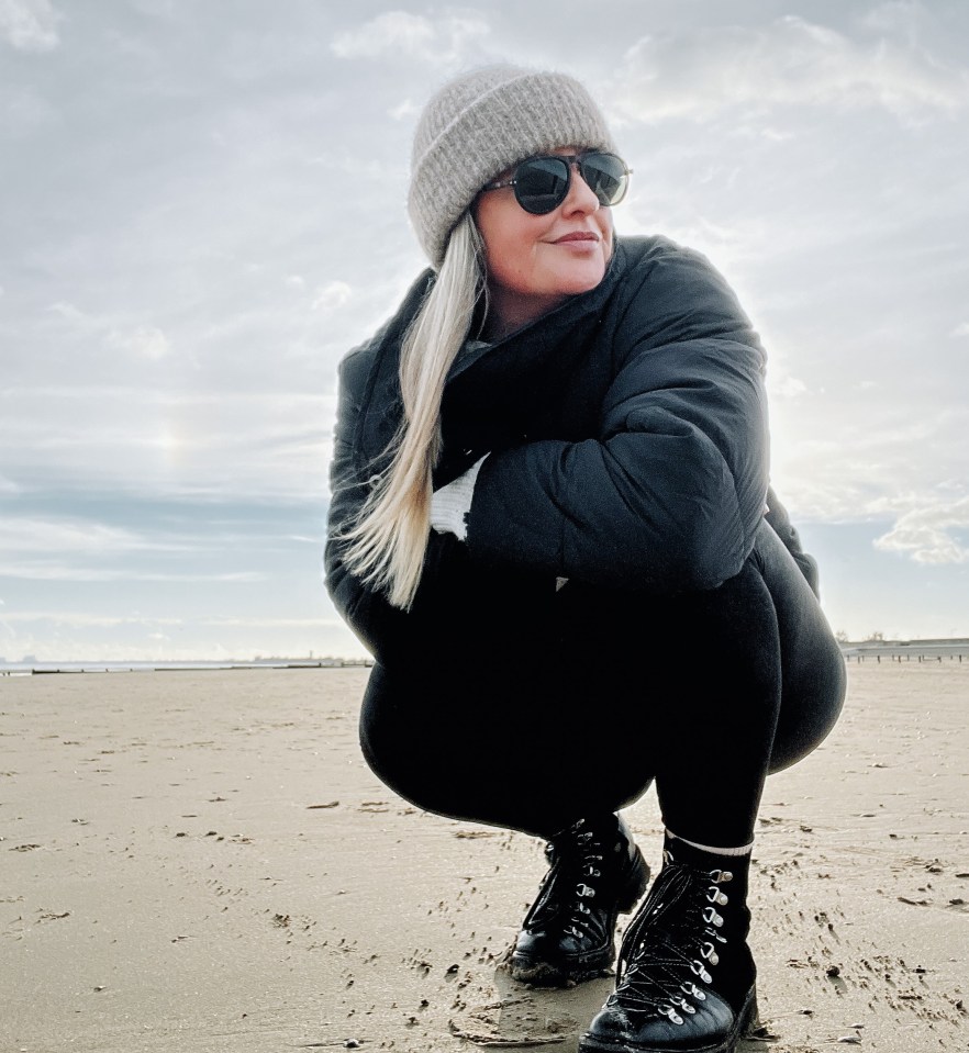 Woman crouching on a beach.