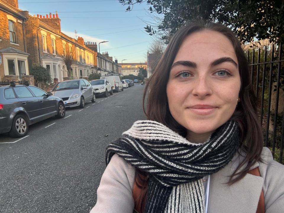 Woman in a scarf standing on a residential street.