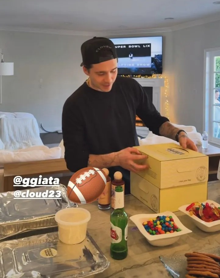 Brooklyn Beckham opening boxes of food and drinks.