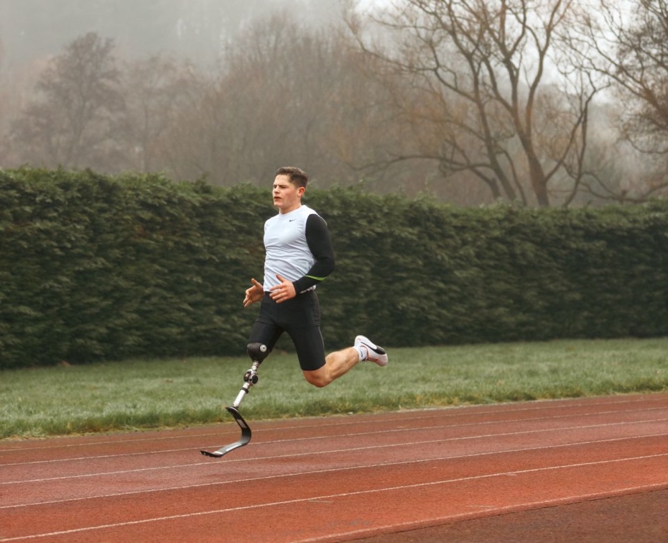 Amputee runner sprinting on a track.