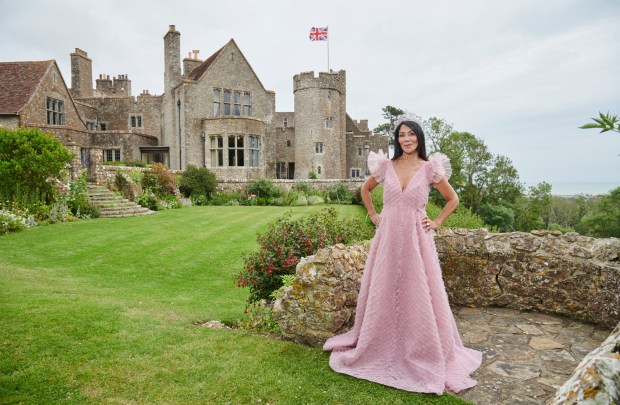 Woman in pink gown and tiara standing in front of Lympne Castle.