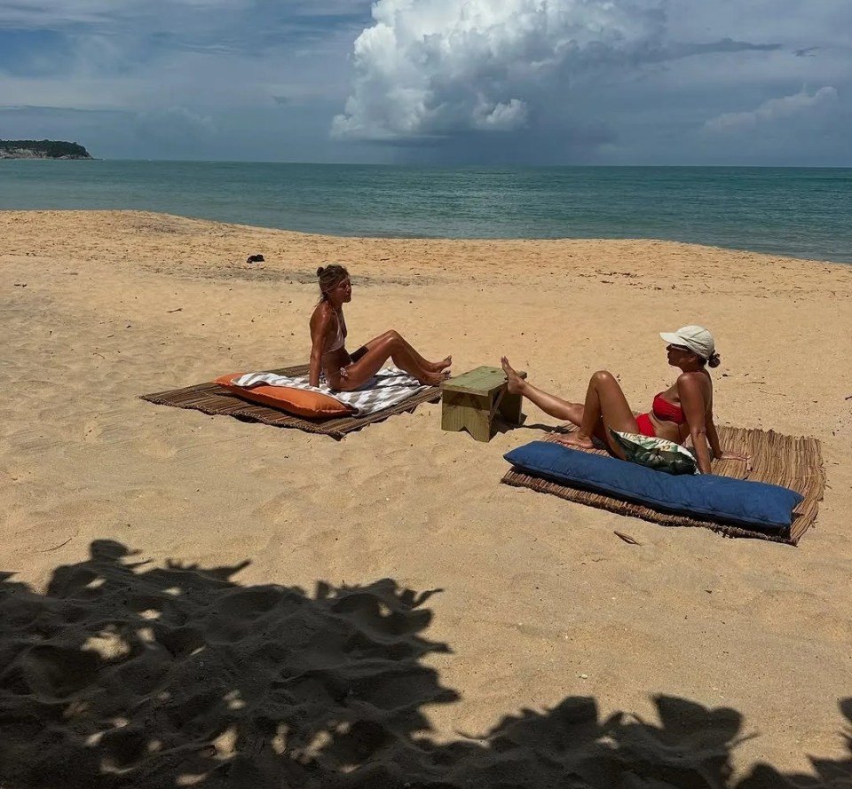 Two women relaxing on a beach in bikinis.