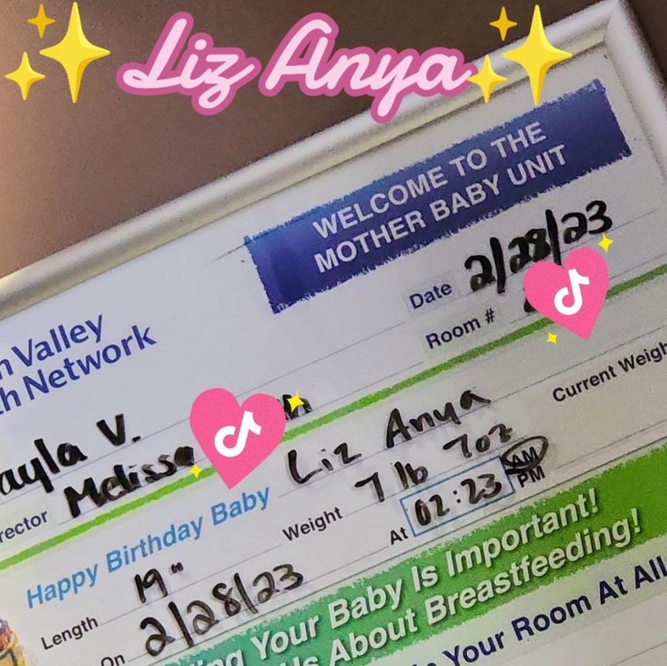 Photo of a whiteboard with a baby's birth information, including the name Liz Anya.