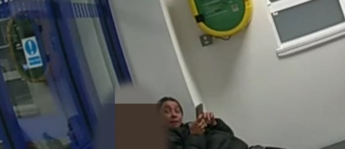 Person using a phone in a waiting area with a defibrillator and knife bank.