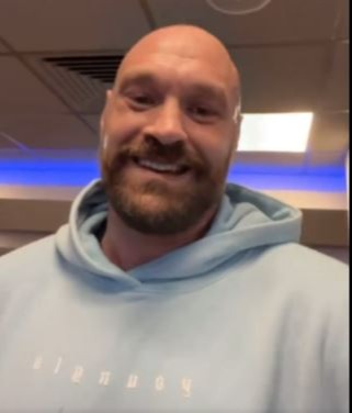 Tyson Fury smiling in a light blue hoodie.