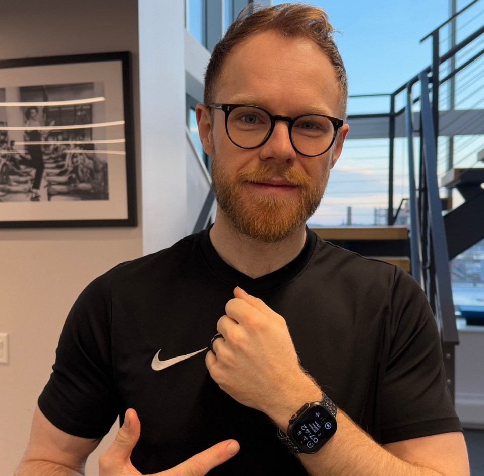 Man wearing glasses and a Nike shirt showing his Apple Watch.