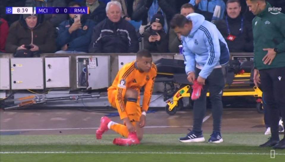 Soccer player adjusting his shoe on the field.