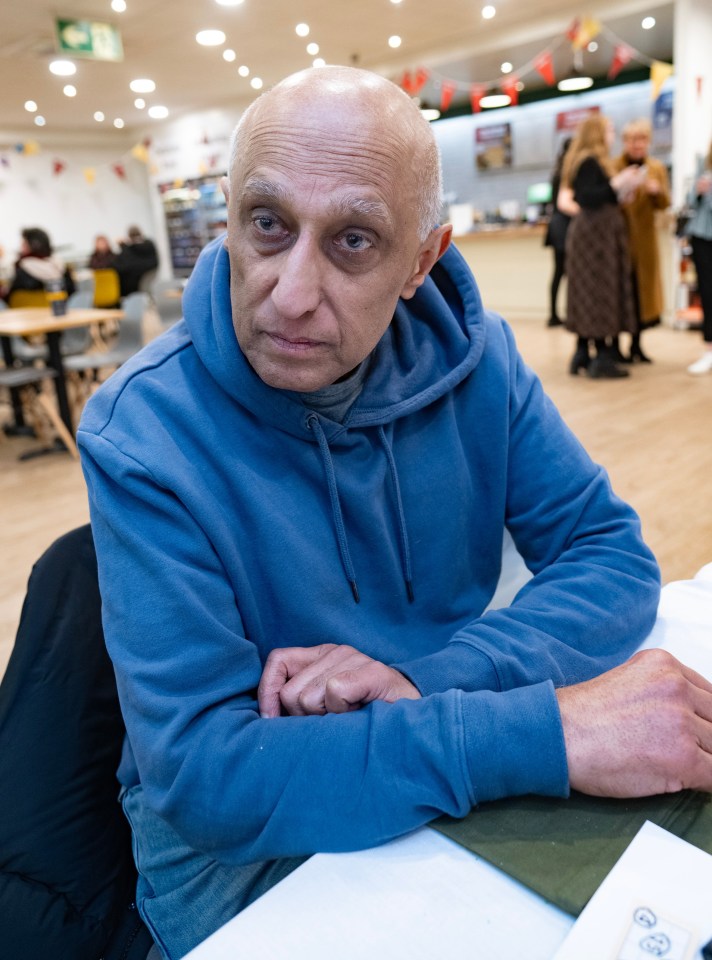 A man in a blue hoodie sits at a table.