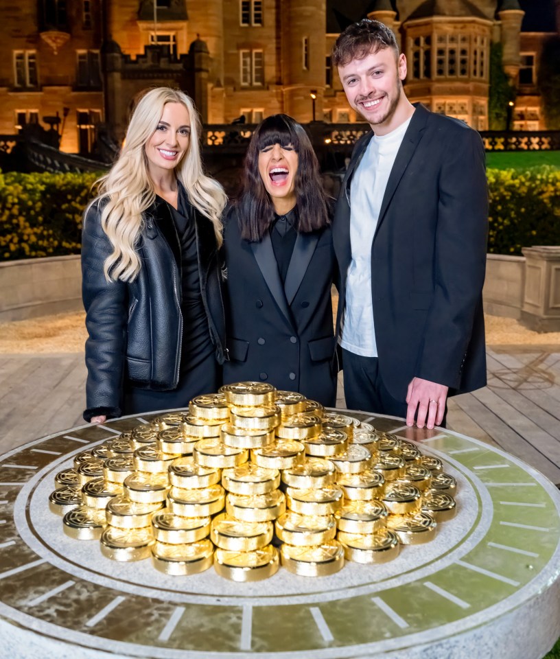 Three presenters stand behind a large pile of gold coins in front of a castle.