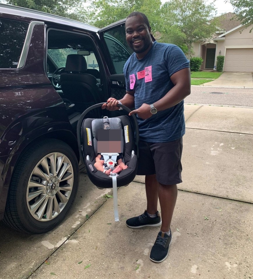 Man holding baby car seat with newborn inside.