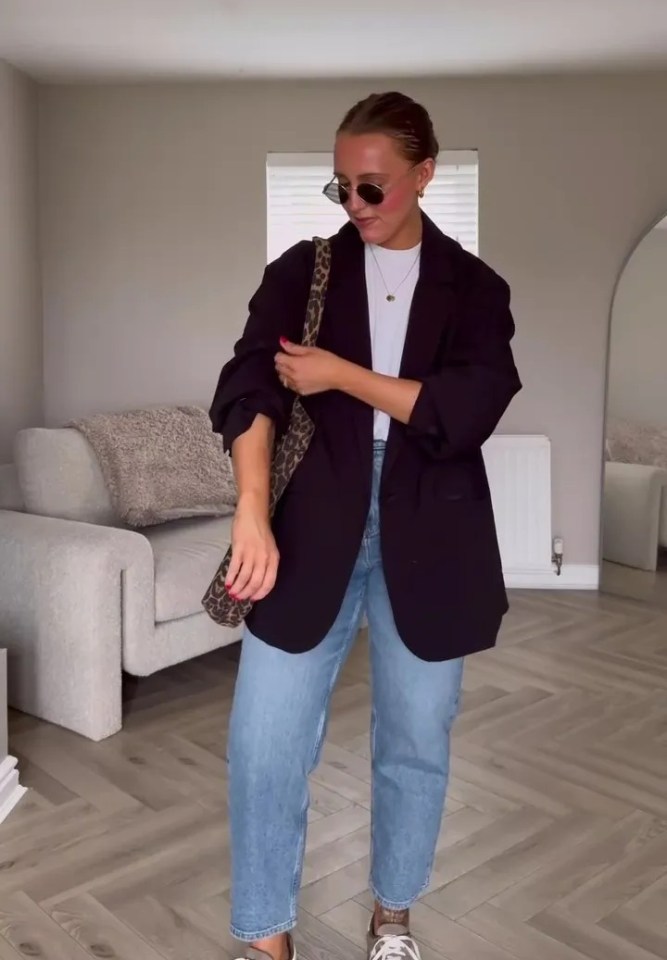 Woman in a blazer, light wash jeans, and sneakers.