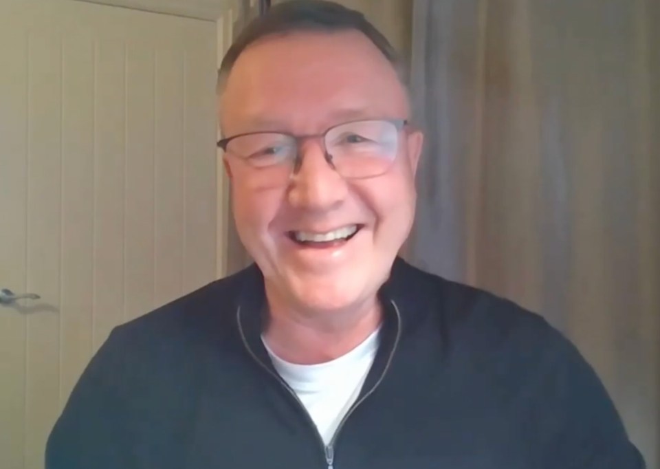 Screenshot of a man laughing during a video interview.