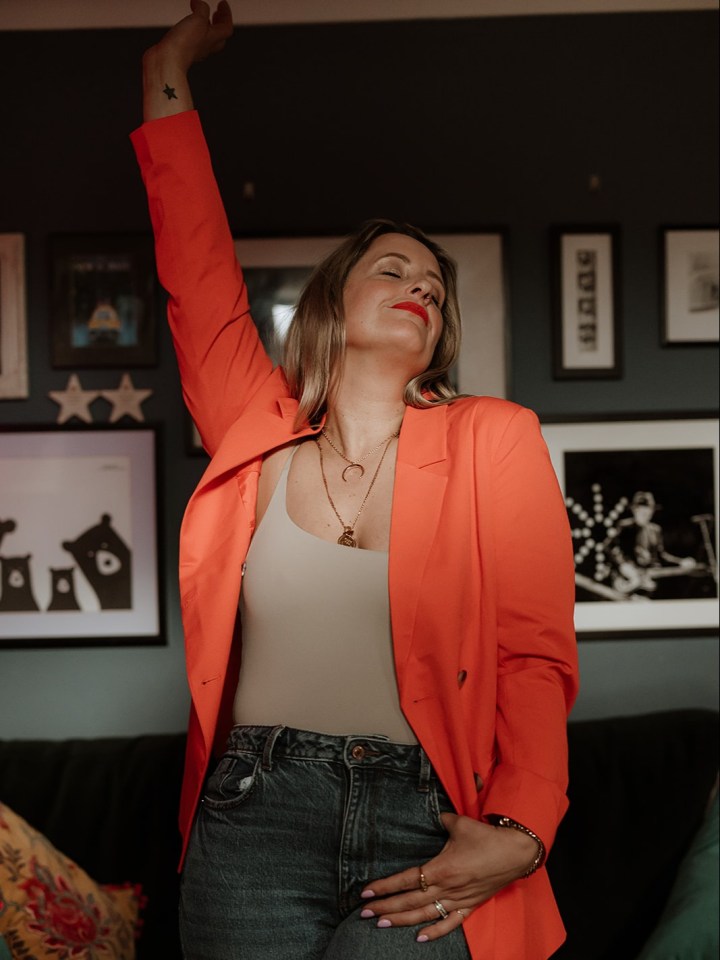 Woman in orange blazer stretching.