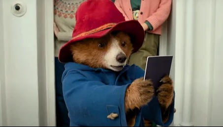 Paddington Bear looking at a card.