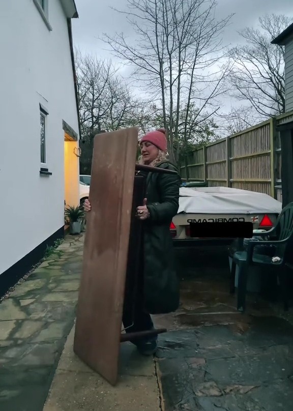 Woman carrying a large wooden table.