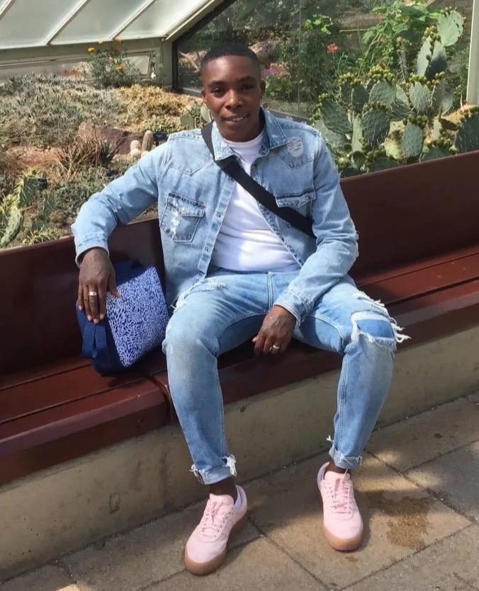 Person sitting on a bench wearing light wash jeans and a denim jacket.