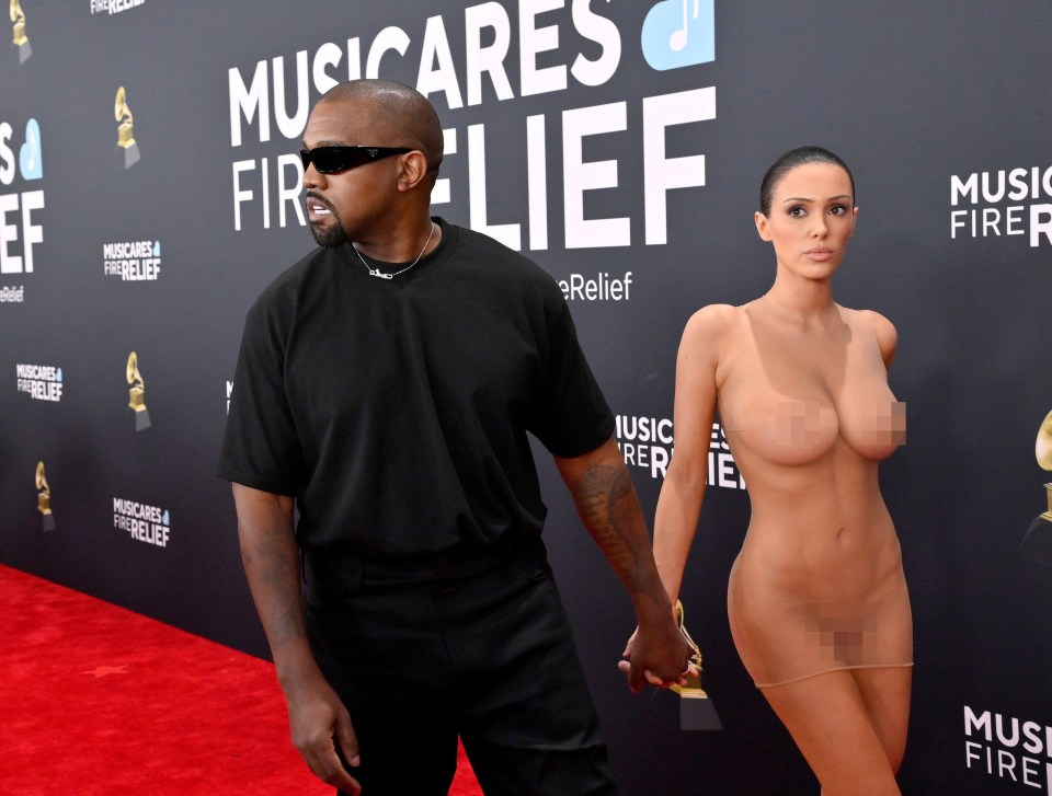 Kanye West and a woman holding hands on a red carpet.