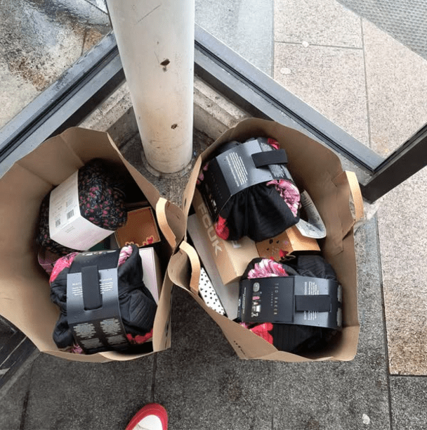 Two shopping bags overflowing with clothing and gifts.