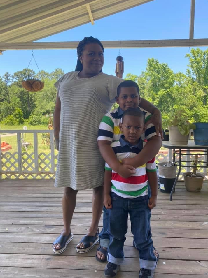 A woman and her two sons on a porch.