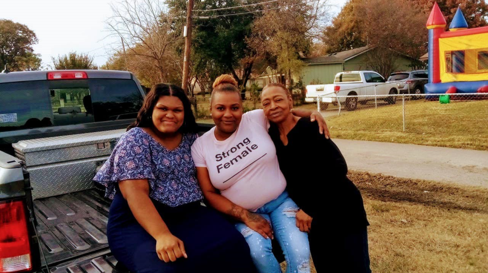 Three generations of women posing together.