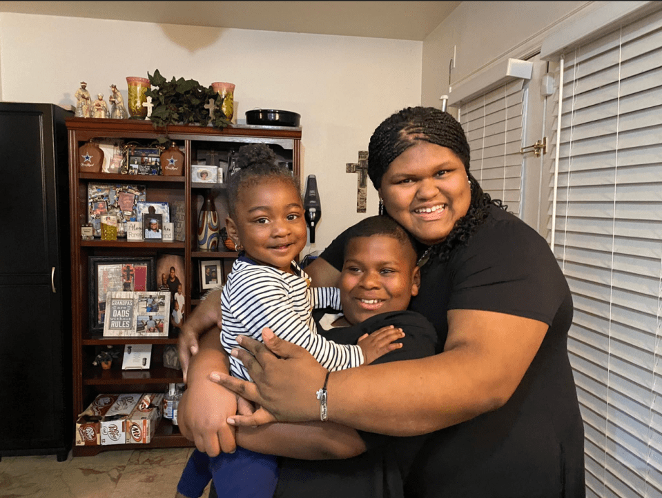 A woman hugging her young son and daughter.