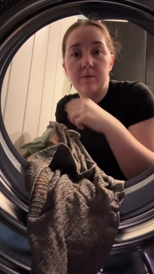 Person removing a dirty towel from a washing machine.